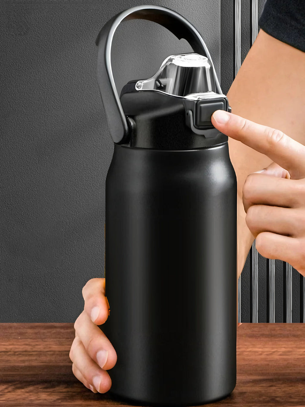 Gourde isotherme à paille et anse, 800 ml à 1,5 L : Noir en main, doigt sur le bouton