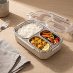 Boîte repas inox ouverte, couvercle posé à côté, trois compartiments garnis de riz, légumes et pois chiches