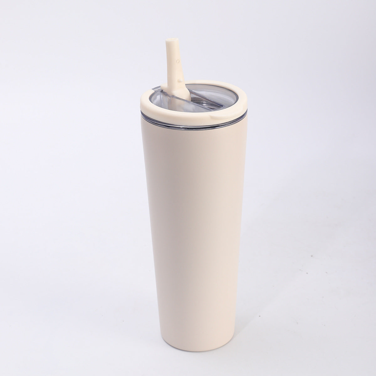Packshot solo trois-quarts d'un gobelet conique crème, couvercle transparent à collerette silicone et paille inclinée.