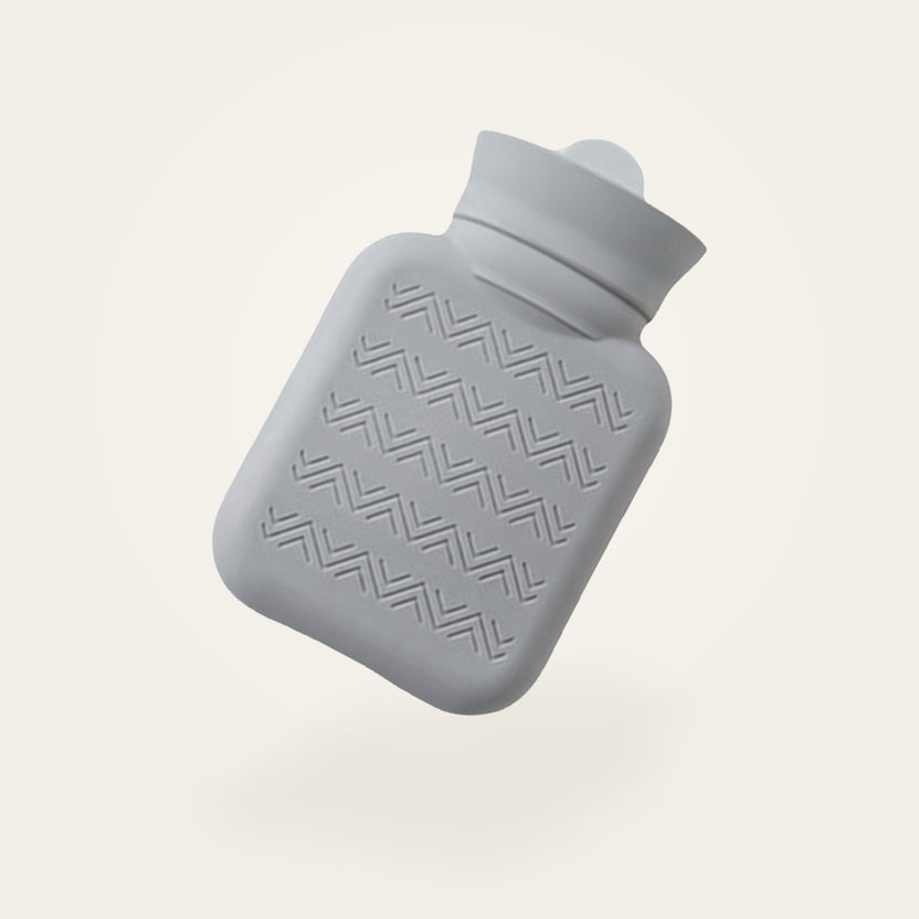 Bouillotte à eau en silicone gris clair, sans sa housse, fond crème