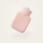 Bouillotte à eau en silicone rose, sans sa housse, fond crème