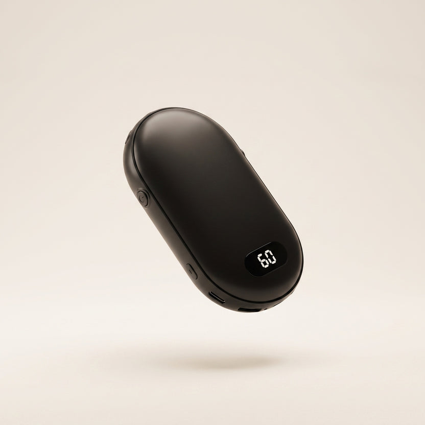 Galet chauffe-mains rechargeable noir avec écran LED, vue de trois quarts sur fond crème