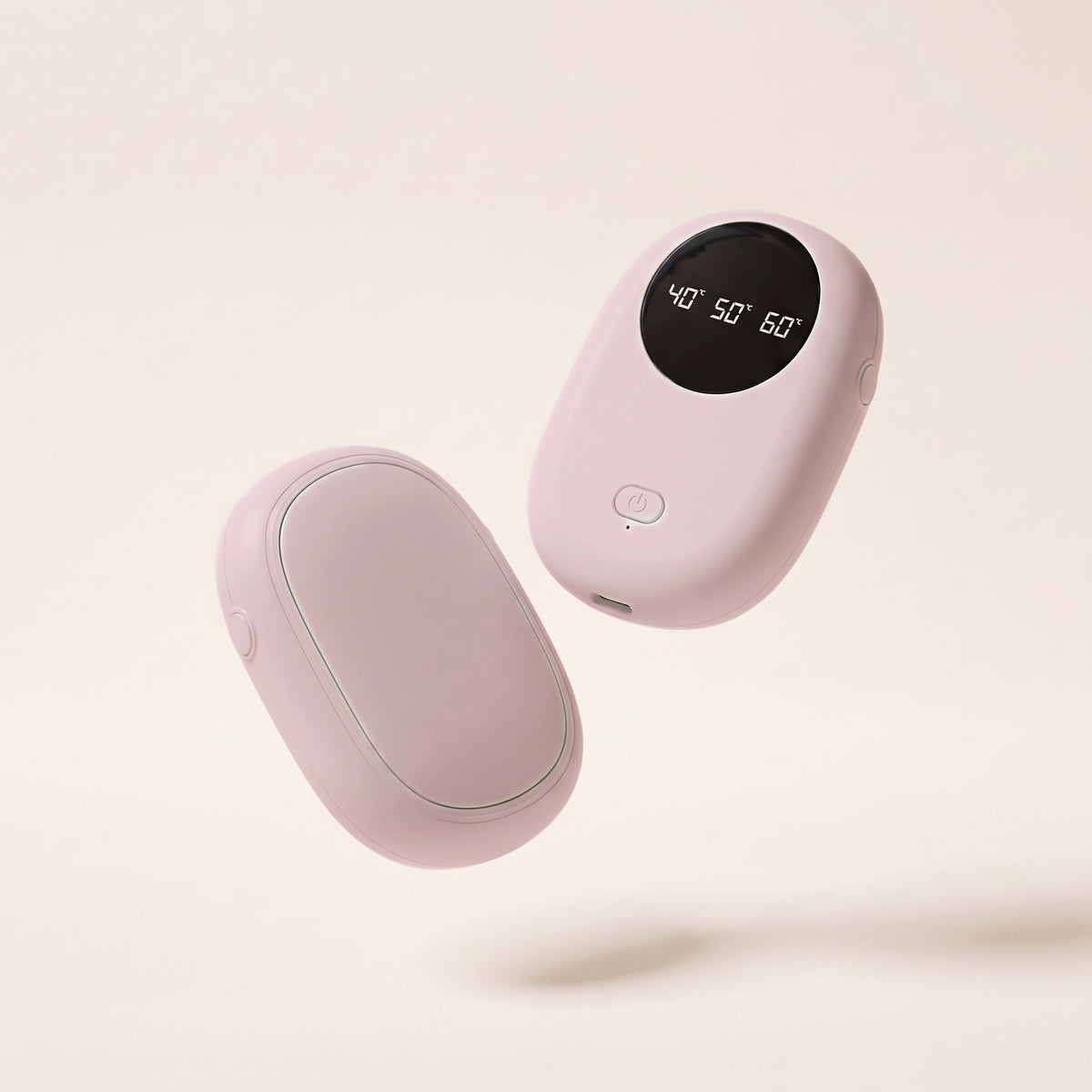 Chauffe-mains de poche rose en deux modules, écran de réglage allumé, fond crème