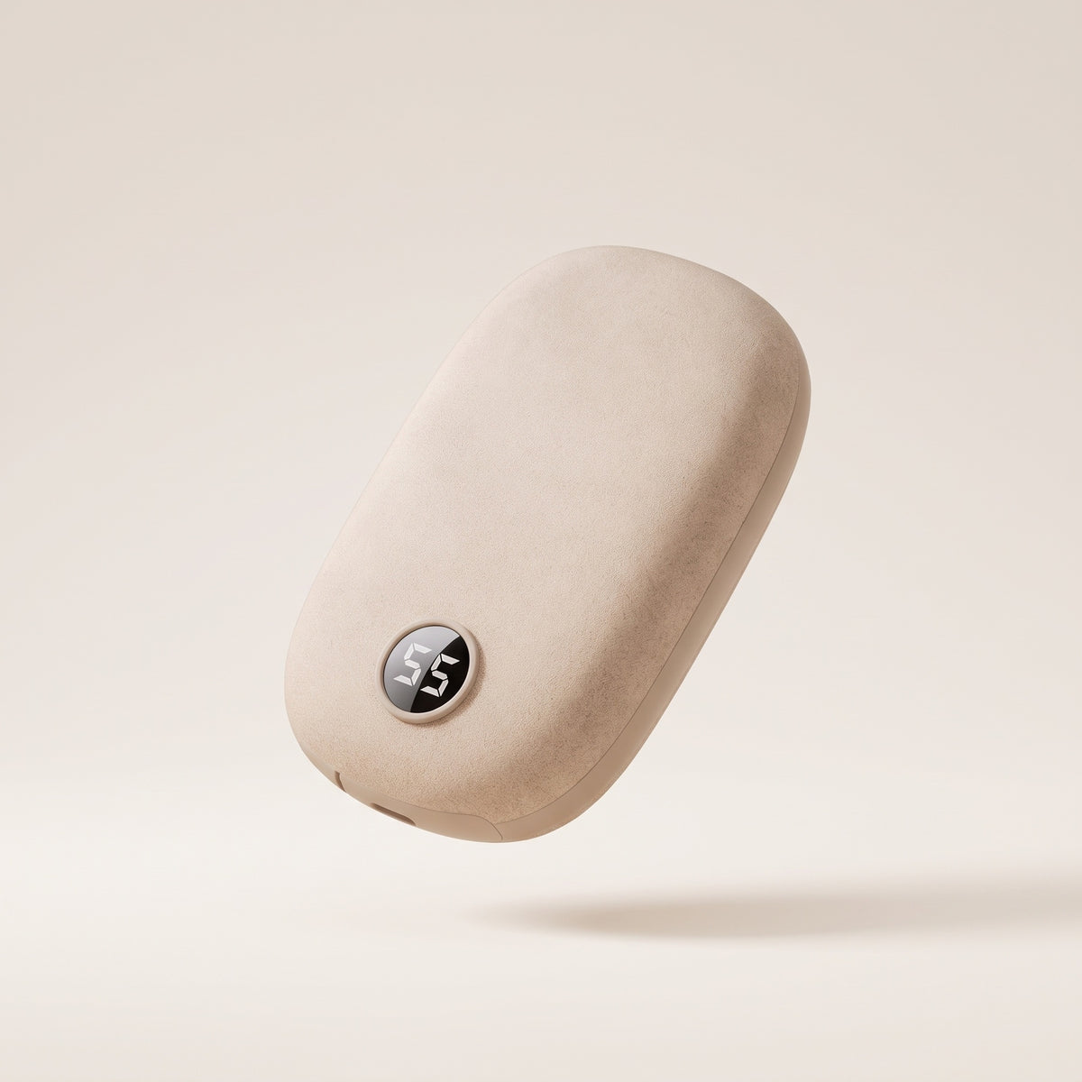 Chauffe-mains rechargeable en suédine beige, écran affichant 55, vue de trois quarts sur fond crème