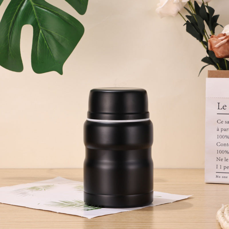 Pot noir mat uni sur fond beige avec monstera et sac kraft, rendu très sobre.